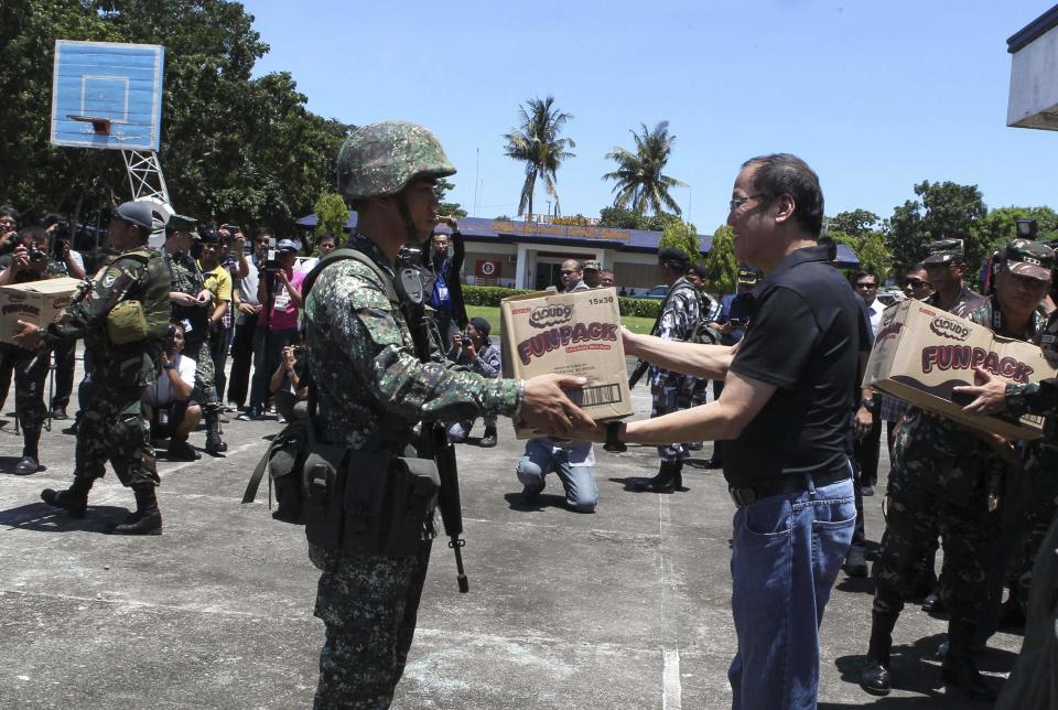 Philippine President Benigno Aquino (R) distributes supplies to government forces during a visit to assess the situation of the standoff between the Moro National Liberation Front (MNLF) and government forces, in Zamboanga city, southern Philippines in this September 13, 2013 handout provided by the Presidential Palace. Local government officials said evacuees have reached to about 20,000 people, as a government standoff with the MNLF seeking an independent state reaches its fifth day. REUTERS/Presidential Palace/Handout via Reuters (PHILIPPINES - Tags: POLITICS MILITARY CIVIL UNREST) ATTENTION EDITORS - THIS IMAGE WAS PROVIDED BY A THIRD PARTY. FOR EDITORIAL USE ONLY. NOT FOR SALE FOR MARKETING OR ADVERTISING CAMPAIGNS. THIS PICTURE IS DISTRIBUTED EXACTLY AS RECEIVED BY REUTERS, AS A SERVICE TO CLIENTS. NO SALES. NO ARCHIVES