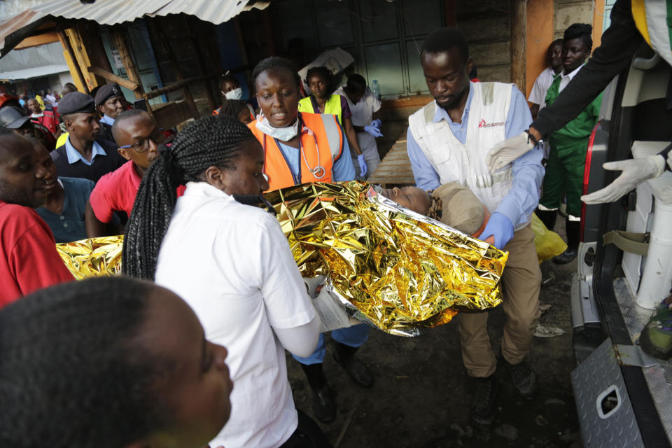 Rescue workers carry a person rescued from the rubble of a building that collapsed in Tasia Embakasi, an east neighbourhood of Nairobi, Kenya on Friday Dec. 6, 2019. A six-story building collapsed in Kenya's capital on Friday, officials said, with people feared to be trapped in the debris. Police say people have been rescued by residents using their bare hands. (AP Photo/Khalil Senosi)