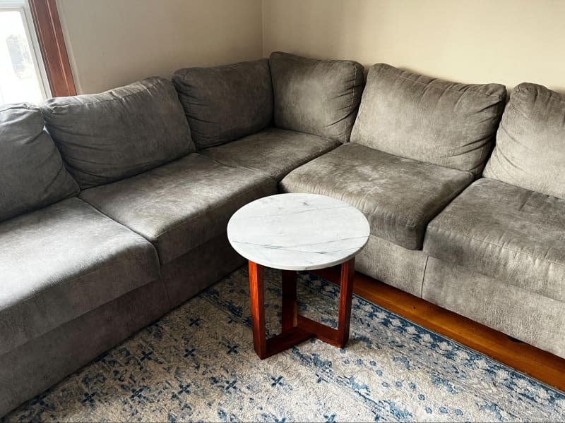 Marble top side table in front of living room sectional.