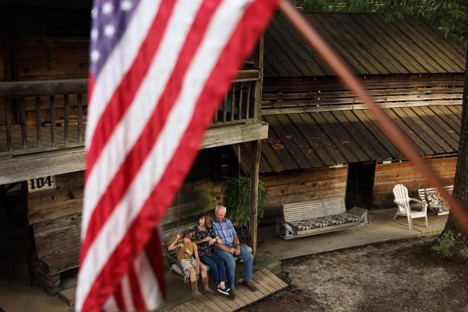 A family sits on the porch of their tent at Rock Springs Camp Meeting in Denver, N.C., on Friday, August 10, 2023.