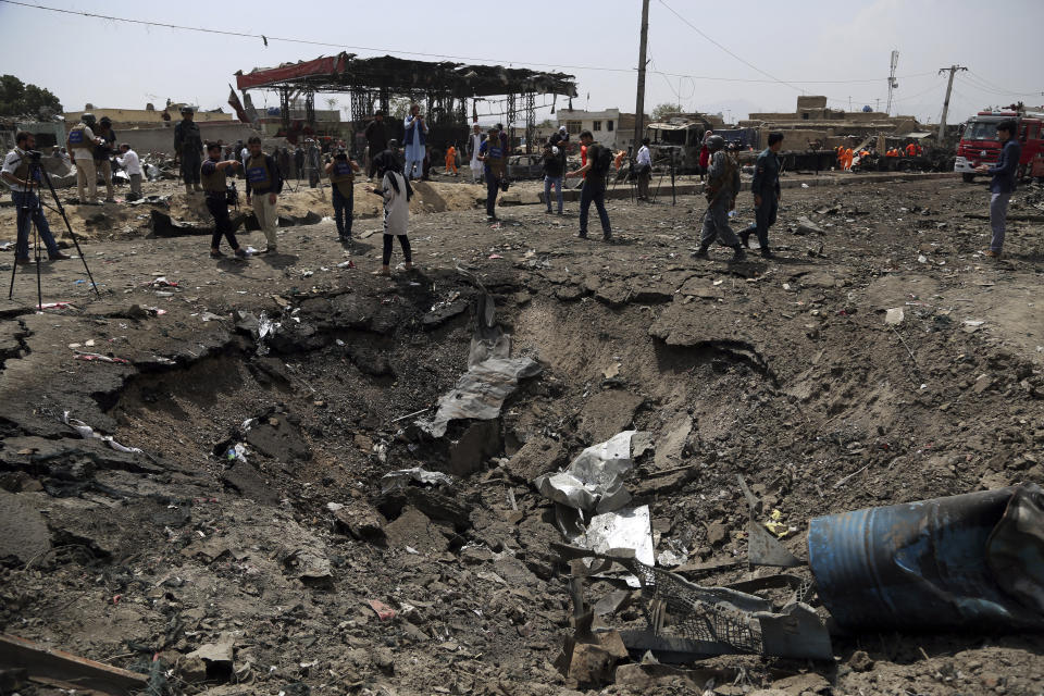 Journalists and security forces stand next to a crater caused by Monday's suicide bomb attack in Kabul, Afghanistan, Tuesday, Sept. 3, 2019. The attack occurred late Monday near the the Green Village, home to several international organizations and guesthouses. (AP Photo/Rahmat Gul)