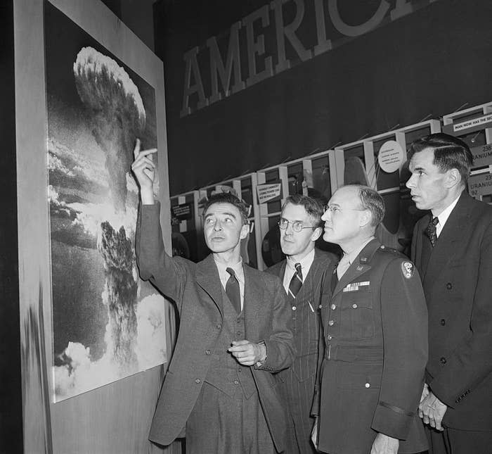 Oppenheimer and other men looking at a poster of the blast