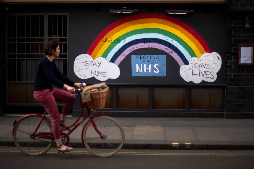 A woman cycles past a rainbow graffiti in support of the NHS in Soho (PA) (PA Archive)