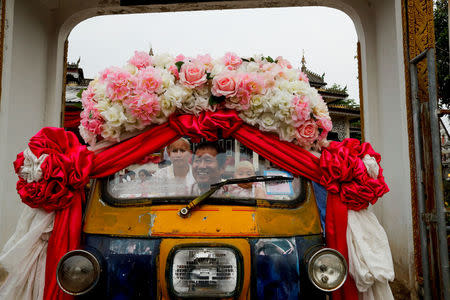 Mr. Kasem rides a tuk-tuk carrying his new ordained sons Apiwvit and Phusit after their heads were shaved at Wat Klang Thung temple in preparation for an annual Poy Sang Long celebration, part of the traditional rite of passage for boys to be initiated as Buddhist novices, in Mae Hong Son, Thailand, April 2, 2018. REUTERS/Jorge Silva