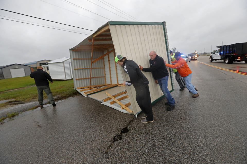 People move a wood and metal structure off a roadway after winds blew it off a sales lot in Florence, South Carolina.