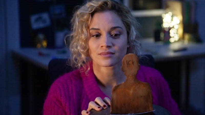 A woman looks at a wooden cutout of a man from an Advent calendar