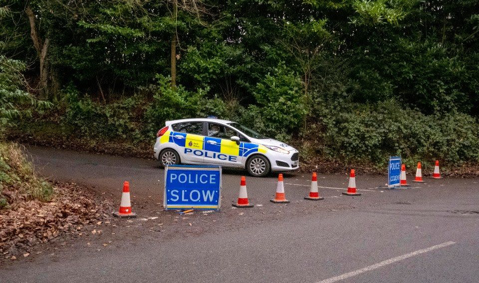 A police car behind a line of cones and sign that reads "police slow"