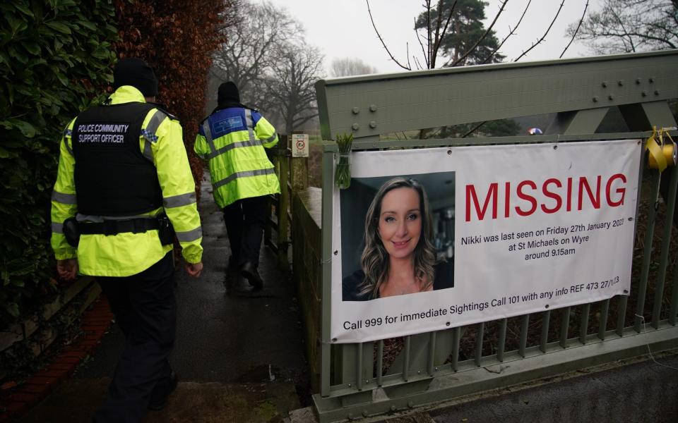 Police officers walk past a missing person appeal poster for Nicola Bulley tied to a bridge over the River Wyre - Peter Byrne /PA