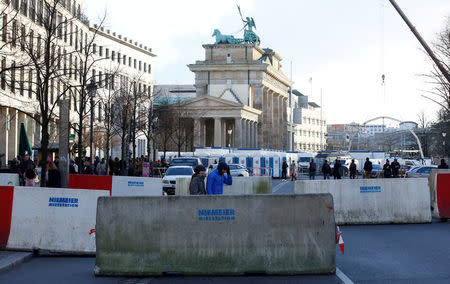 People walk beside concrete barriers at the Brandenburg Gate, ahead of the upcoming New Year's Eve celebrations in Berlin, Germany December 27, 2016. REUTERS/Fabrizio Bensch/Files