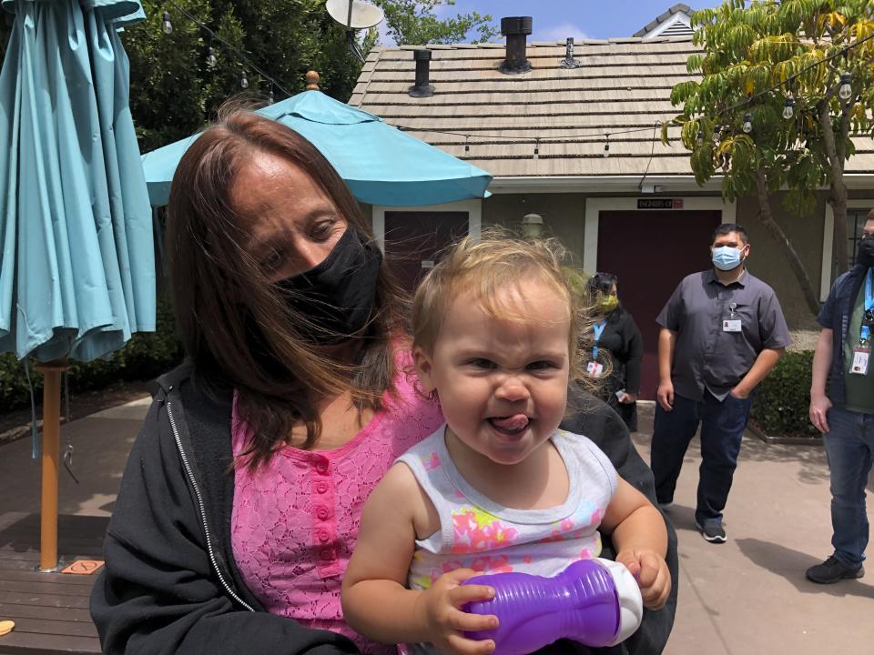 Lindsey Prescott looks at her 18-month-old daughter, Mia, as she giggles on Tuesday, May 11, 2021 in San Diego. Prescott moved into a converted San Diego hotel that Gov. Gavin Newsom visited Tuesday to announce a $12 billion program to get people like Prescott off the streets. (AP Photo/Julie Watson)