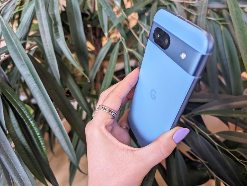 Google Pixel 8a held in hand with purple nails