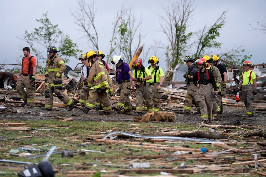 Firefighters walks among tornado-damaged homes, Tuesday, May 21, 2024, in Greenfield, Iowa. (AP Photo/Charlie Neibergall)