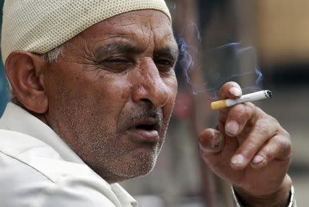 A man smokes a cigarette as he sits on a pavement along a road in Srinagar September 4, 2012. REUTERS/Fayaz Kabli/Files