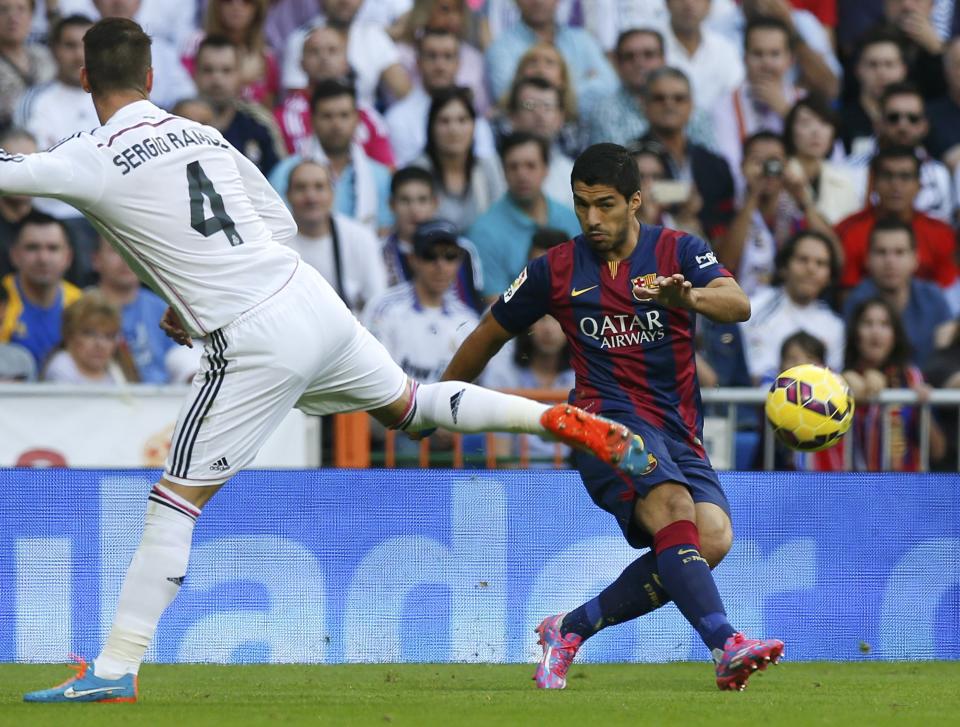 Barcelona's Luis Suarez (R) kicks the ball past Real Madrid's Sergio Ramos during their Spanish first division "Clasico" soccer match at the Santiago Bernabeu stadium in Madrid October 25, 2014. REUTERS/Sergio Perez (SPAIN - Tags: SOCCER SPORT)