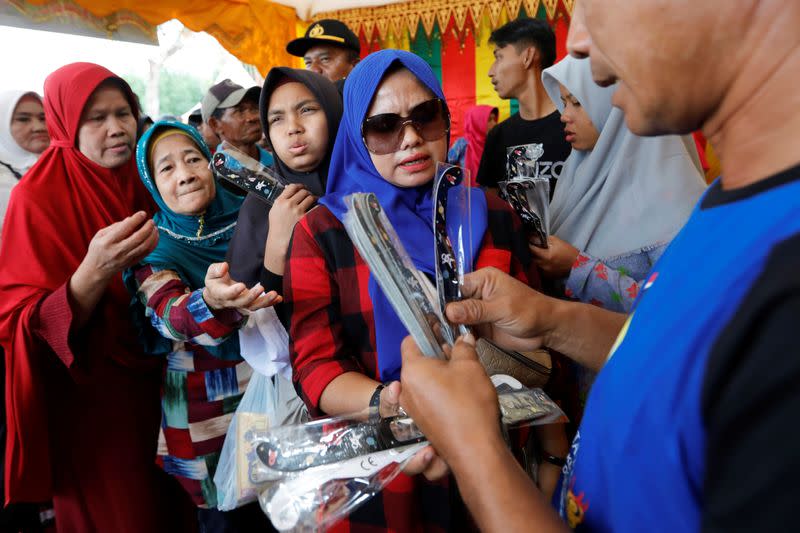 People queue for free special protective glasses for solar eclipse, given by local government, during the annular solar eclipse in Siak