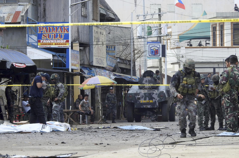 Police investigators and soldiers attend the scene after two bombs exploded outside a Roman Catholic cathedral in Jolo, the capital of Sulu province in southern Philippines, Sunday, Jan. 27, 2019. Two bombs minutes apart tore through a Roman Catholic cathedral on a southern Philippine island where Muslim militants are active, killing at least 20 people and wounding more than 80 others during a Sunday Mass, officials said. (AP Photo/Nickee Butlangan)