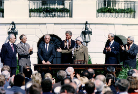 FILE PHOTO: PLO Chairman Yasser Arafat (3rd R) gestures to Israeli Prime Minister Yitzhak Rabin (3rd L), as U.S. President Bill Clinton (C) stands between them, following their handshake after the signing of the Israeli-PLO peace accord, at the White House in Washington, U.S., September 13, 1993. Also on stage are Israeli Foreign Minister Shimon Peres (L), U.S. Secretary of State Warren Christopher (2nd R) and Palestinian negotiator Mahmoud Abbas (R). REUTERS/Gary Hershorn/File Photo