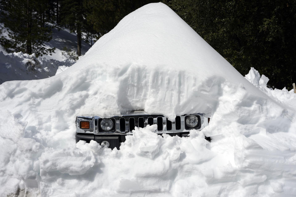 A vehicle's grill sticks out of a snow mound after a series of storms, Wednesday, March 8, 2023, in Lake Arrowhead, Calif. (AP Photo/Marcio Jose Sanchez)