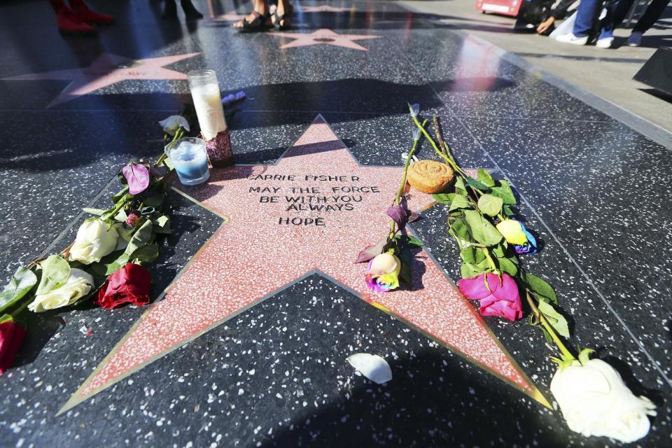 Flowers and candles adorn an impromptu memorial created on a blank Hollywood Walk of Fame star by fans of late actress and author Carrie Fisher, who does not have an official star on the world-famous promenade, in Los Angeles Wednesday, Dec. 28, 2016. Paste-on letters spell out her name and the phrase "May the force be with you always. Hope." (AP Photo/Reed Saxon)