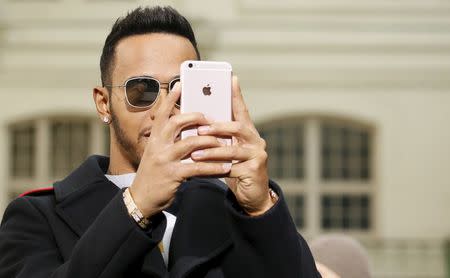 Formula One driver Lewis Hamilton takes a picture with his mobile phone as he attends designer Bill Gaytten's Fall/Winter 2016/2017 women's ready-to-wear collection for fashion house John Galliano in Paris, France, March 6, 2016. REUTERS/Gonzalo Fuentes