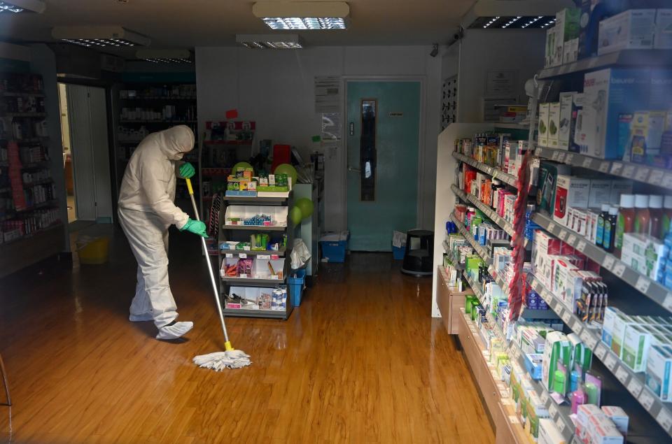 In this photograph taken through a window, a worker in protective clothing, including face mask and gloves, is pictured cleaning the floor of the pharmacy attached to the at the Warmdene doctor's Surgery at County Oak Medical Centre in Brighton, southern England on February 10, 2020, after it closed for "urgent operational health and safety reasons", following reports a member of staff was infected with the 2019-nCoV strain of the novel coronavirus, Covid-19,. - The British government on Monday warned the outbreak of novel coronavirus was a "serious and imminent threat" and reported four new cases that brought the total recorded in the country to eight. Two hospitals The Royal Free and Guys and St Thomas', have both been designated as "isolation" facilities, with both currently housing Britons who have returned from Wuhan, the Chinese city at the centre of the outbreak. (Photo by Glyn KIRK / AFP) (Photo by GLYN KIRK/AFP via Getty Images)