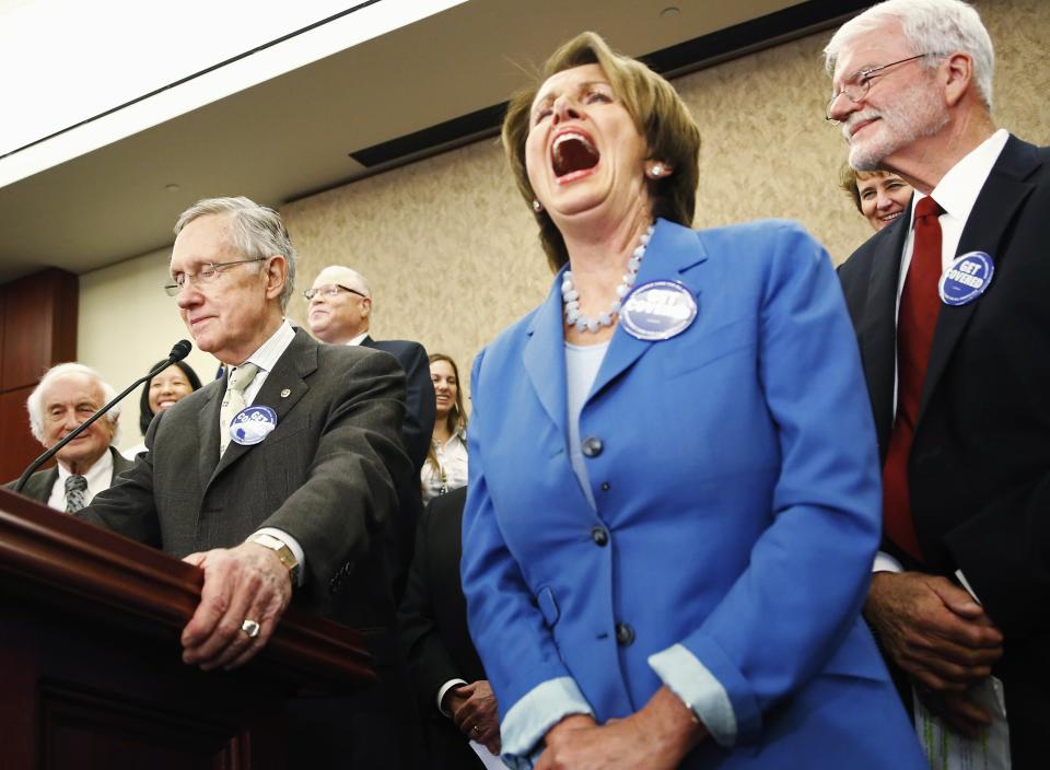 Pelosi laughs as Reid makes a joke at a rally to celebrate the start of Obamacare at the U.S. Capitol in Washington