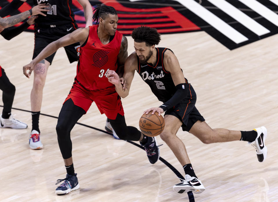 Detroit Pistons guard Cade Cunningham, right, drives to the hoop against Portland Trail Blazers forward Jabari Walker, left, during the first half of an NBA basketball game Thursday, Feb. 8, 2024, in Portland, Ore. (AP Photo/Howard Lao)