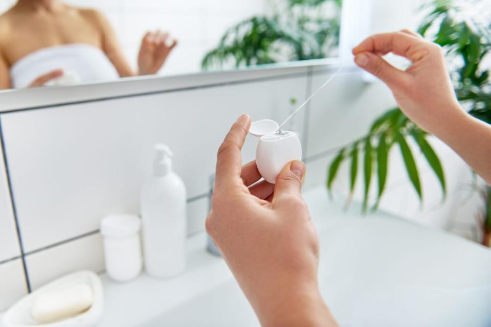 woman holding floss in bathroom scene