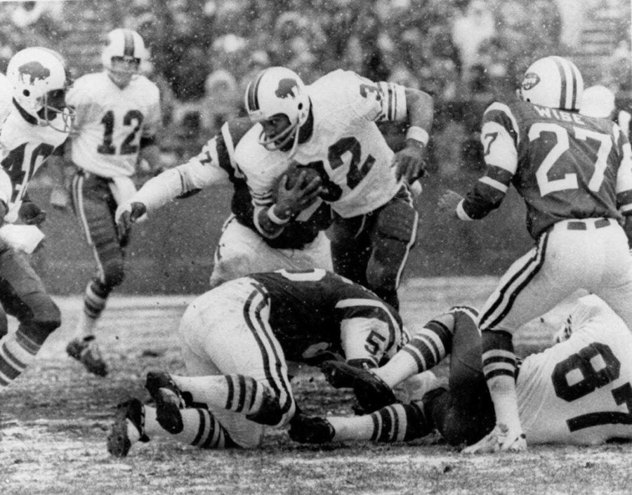 O.J. Simpson of the Buffalo Bills (32) goes through the New York Jets line Dec.16, 1973 at Shea Stadium in New York in the first quarter play in which Simpson broke the NFL season rushing record. Also shown are Joe Ferguson (12) and Paul Seymour (87) of the Bills and Phil Wise (27) and John Ebersole (55) of the Jets. (AP Photo)