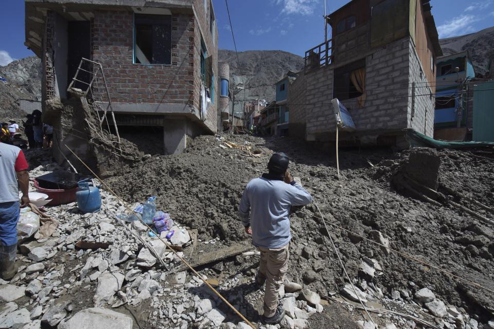 A resident stands outside his home destroyed by a landslide, in Camana, Peru, Tuesday, Feb. 7, 2023. Authorities in Peru say landslides triggered by steady rains swept mud, water and rocks into several villages in the country's southern region. (AP Photo/Jose Sotomayor)