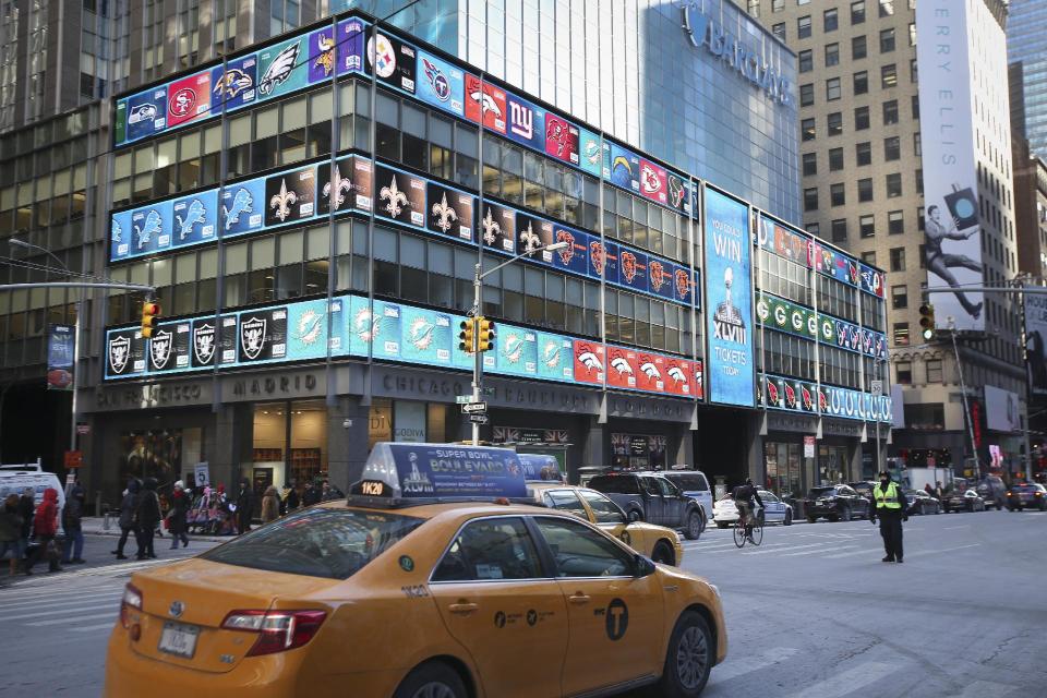 New York yellow cabs pass beneath a display for the NFL Extra Points issued by Barclaycard sweepstakes outside the Barclays Tower near Times Square, Wednesday, Jan. 29, 2014, in New York. NFL Extra Points offered pedestrians a chance to win tickets to Super Bowl XLVIII on Feb. 2 by photographing their favorite team's card and tweeting it. (John Minchillo/AP Images for Barclaycard)