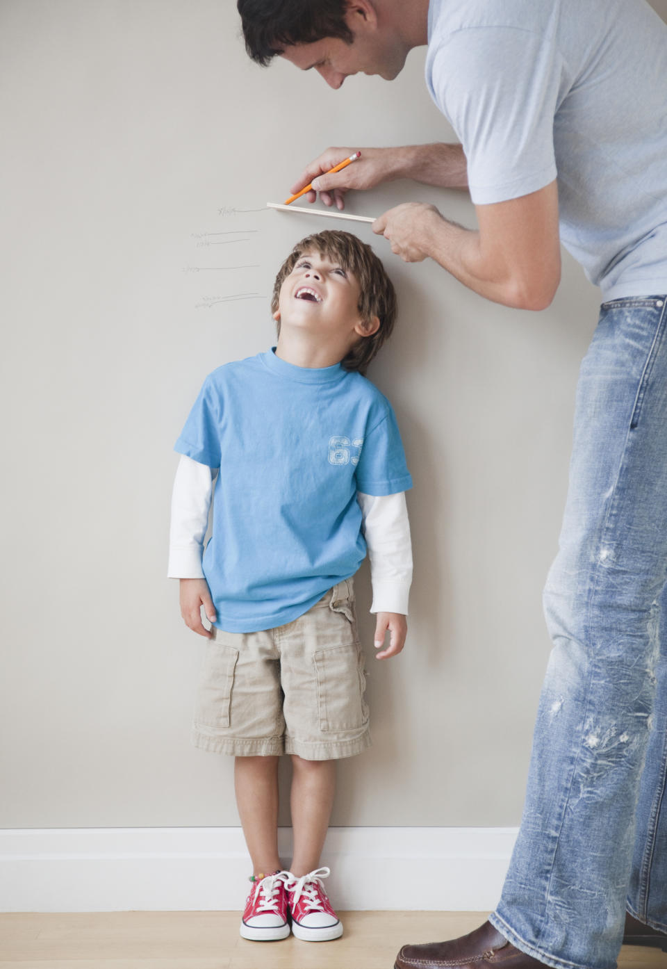 Father measuring son's height against wall