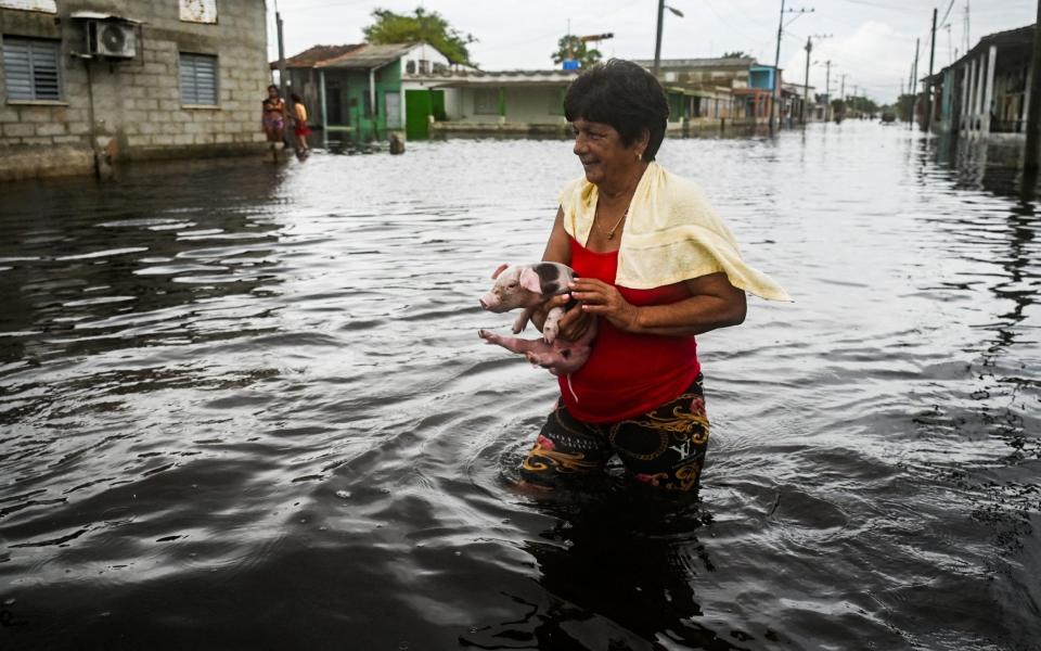 A woman wades through a flooded street in Batabano, Mayabeque province, Cuba