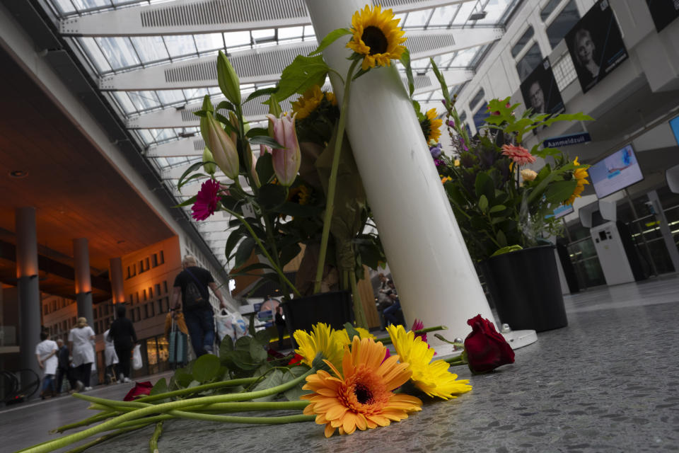 Medical personnel of the Erasmus Medical Centrum passes flowers who were left to commemorate victims of a shooting in Rotterdam, Netherlands, Friday, Sept. 29, 2023. Police in the Netherlands said a lone gunman wearing a bulletproof vest opened fire in an apartment and a hospital in the Dutch port city of Rotterdam, Thursday, Sept. 28, 2023, killing three people, including a 14-year-old girl. (AP Photo/Peter Dejong)