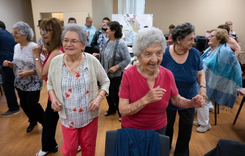 Yolanda Quevedo, de 84 años; Josefina DaVila, de 100, y Augustina Madrid, de 86, cantan y bailan al son de la música interpretada por Liberato Correa durante la reunión semanal de Manitos, un grupo social para personas mayores que hablan español, en el Hart Senior Center, el miércoles 5 de julio de 2023, en Sacramento.