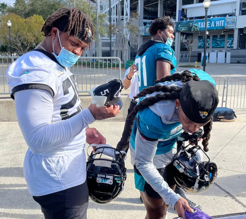 James Robinson (left) and Chris Claybrooks of the Jaguars look at the cleats they will wear on Sunday against the Rams as part of the NFL's "My Cause, My Cleats" program.