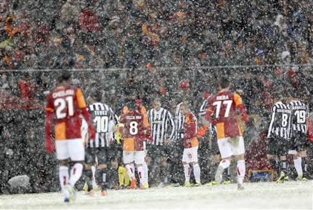 Players of Galatasaray and Juventus walk out of the pitch as their match is paused for 20 minutes due a heavy snowfall during their Champions League soccer match in Istanbul December 10, 2013. REUTERS/Murad Sezer