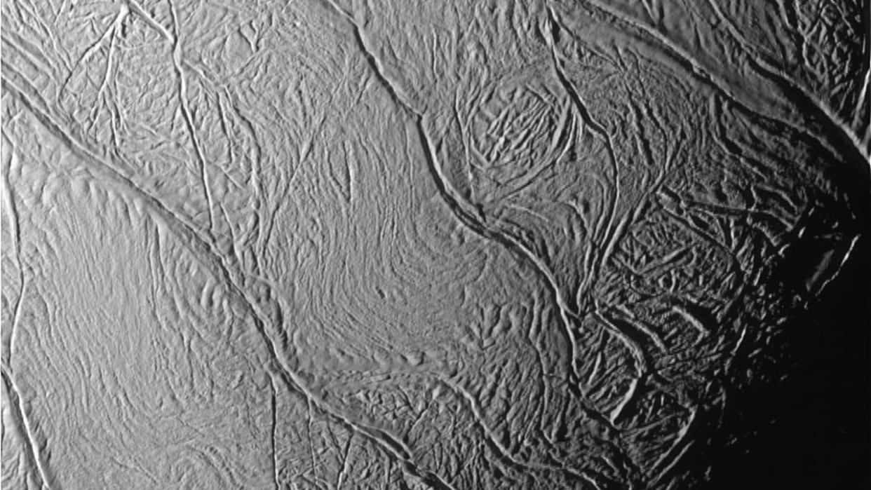 A close up view of an icy moon of saturn showing deep fissures along its surface. 