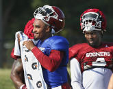 Oklahoma quarterback Jalen Hurts, left, and running back Trey Sermon, right, take a breather during an NCAA college football practice in Norman, Okla., Monday, Aug. 5, 2019. (AP Photo/Sue Ogrocki)