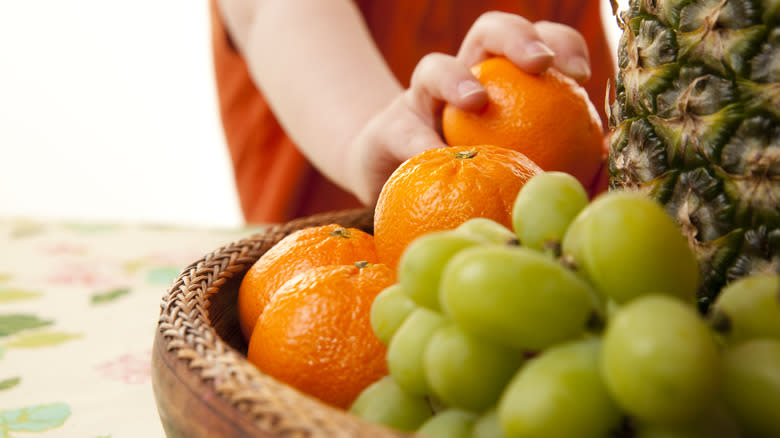 Child grabbing fresh fruit from basket