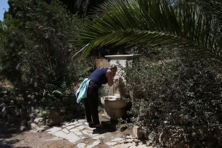 A tourist cools herself in a fountain as she visits the archaeological site of the Temple of Zeus in Athens