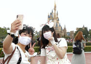 Visitors wearing face masks to protect against the spread of the new coronavirus take a selfie at Tokyo Disneyland in Urayasu, near Tokyo, Wednesday, July 1, 2020. Tokyo Disneyland reopens for the first time in four months after suspending operations due to coronavirus concerns. (Kyodo News via AP)