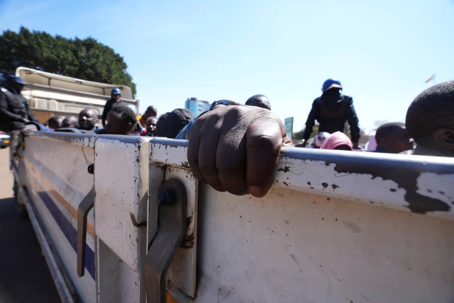 An opposition supporter holds onto a police truck during a court appearance at the magistrates courts in Harare, Thursday, Aug, 17 2023. (AP Photo/Tsvangirayi Mukwazhi)