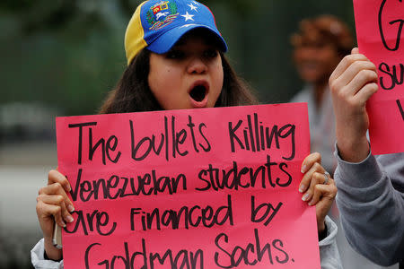 A protester holds a sign as she demonstrates outside of Goldman Sachs headquarters after the company purchased Venezuelan bonds in New York, U.S., May 30, 2017. REUTERS/Lucas Jackson