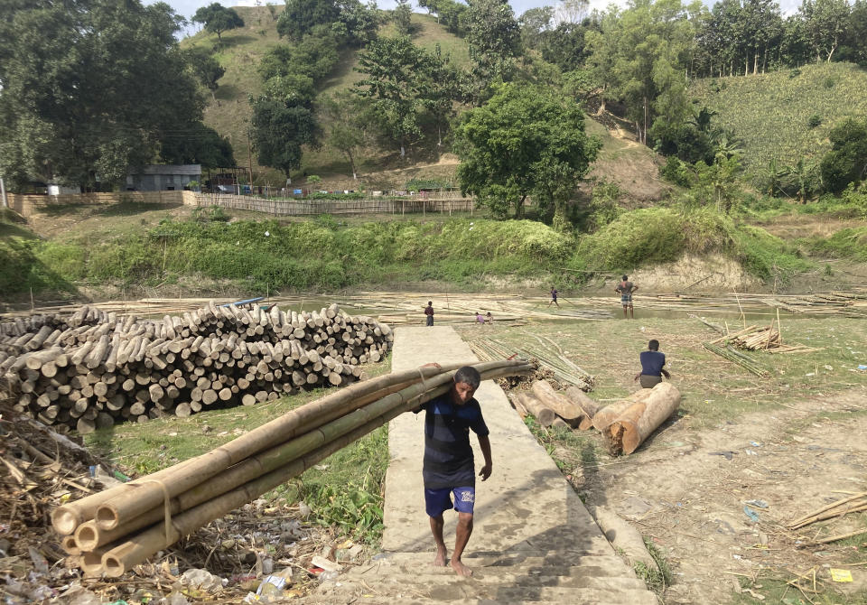 A Chakma tribal carries wooden logs for transporting through river in Rangamati district of Bangladesh, Tuesday, Nov. 29, 2022. Bangladesh is marking 25 years since it signed a peace treaty to end an armed insurgency in southeastern Bangladesh. (AP Photo/Al-emrun Garjon)