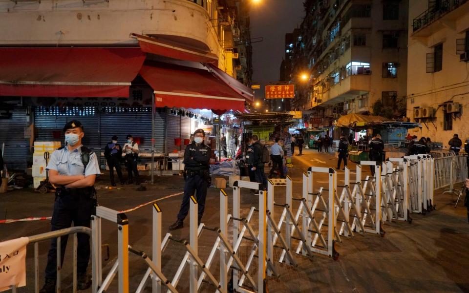 Police officers stand guard at the closed area of Sham Shui Po district - Kin Cheung/AP