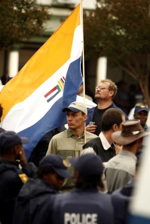 FILE PHOTO: The apartheid-era South African national flag is flown by a supporter of the AWB as police look on outside a South African in Ventersdorp, in the North West Province