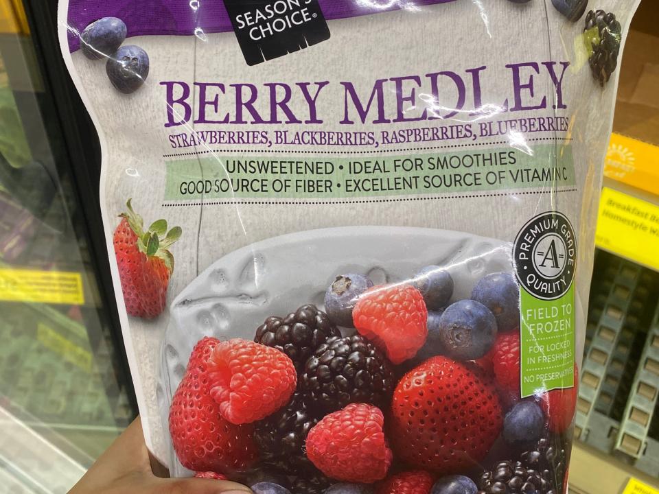 Hand holding a pack of frozen berry medley at Aldi
