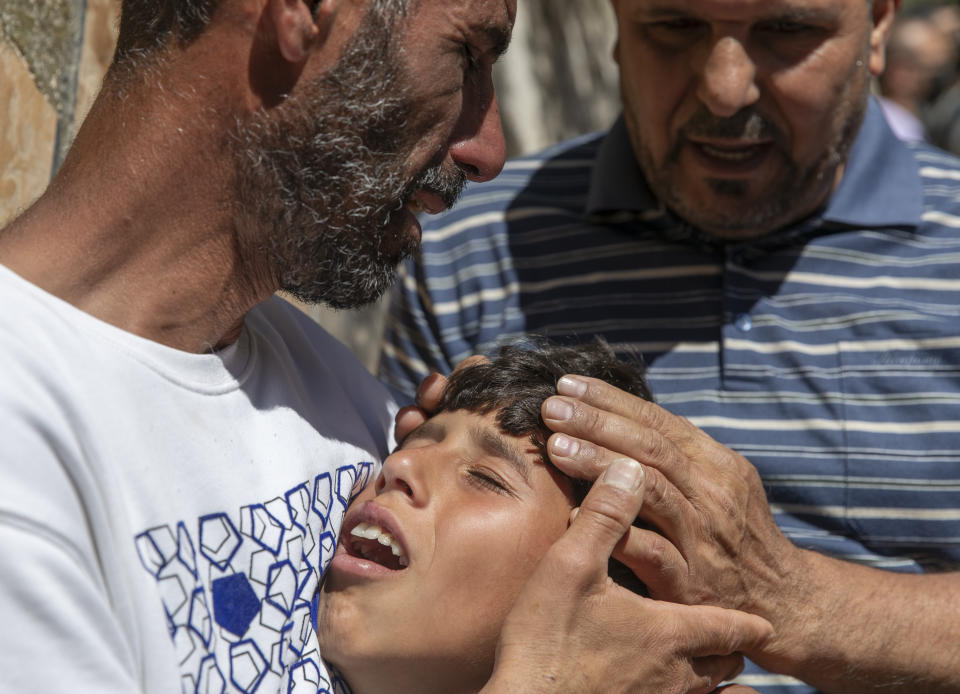 Palestinian Wael Bernat, left, comforts his crying son Ahmad during the funeral of his other son Islam Bernat, 16, in the West Bank city of Ramallah, Wednesday, May 19, 2021. Multiple protesters were killed and more than 140 wounded in clashes with Israeli troops in Ramallah, Bethlehem, Hebron and other cities on Tuesday, according to the Palestinian Health Ministry. The Israeli army said at least a few soldiers were wounded in Ramallah by gunshots to the leg. (AP Photo/Nasser Nasser)