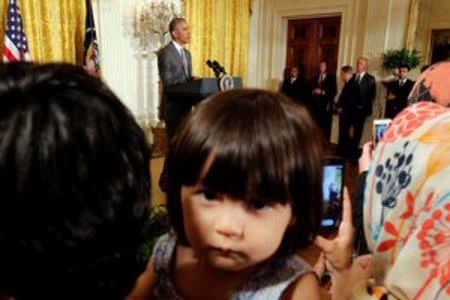 Sophia Ahmadinejad, 2-year-old, a refugee from Afghanistan listens as U.S. President Barack Obama delivers remarks at an Eid al-Fitr reception at the White House in Washington, U.S., July 21, 2016. REUTERS/Carlos Barria